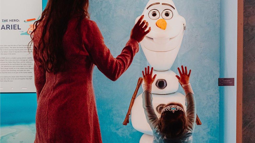 Woman and young girl looking at Olaf model in Frozen exhibit