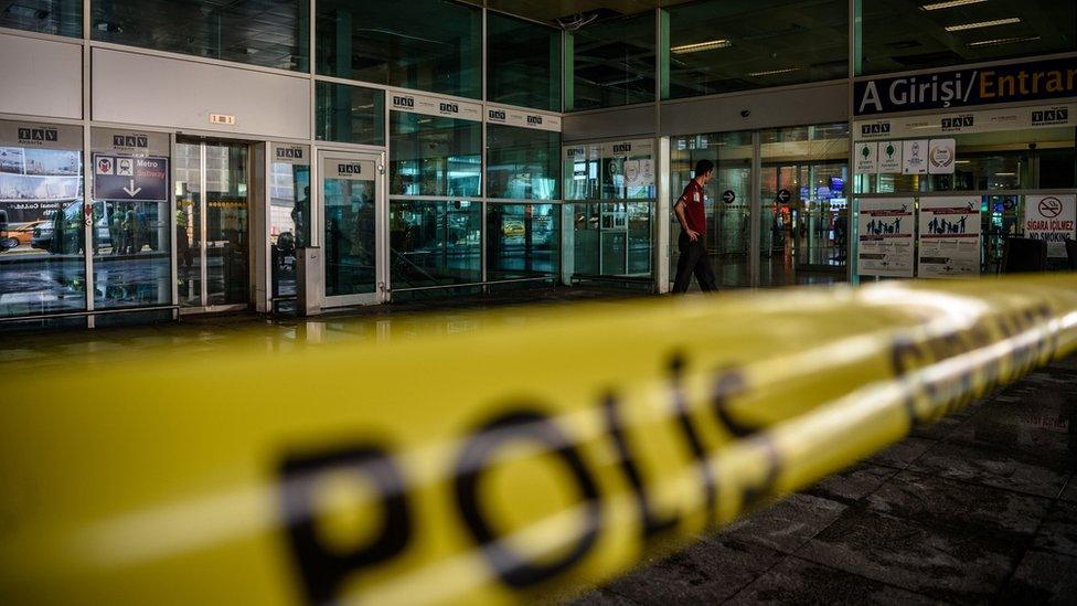 An employee of a private security company patrols outside Ataturk airport's international arrivals terminal on 29 June