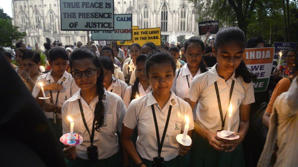 School girls hold candles and placards during the march against rape