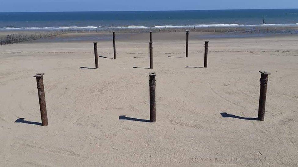 Pier struts stick out from the sand on Colwyn Bay beach