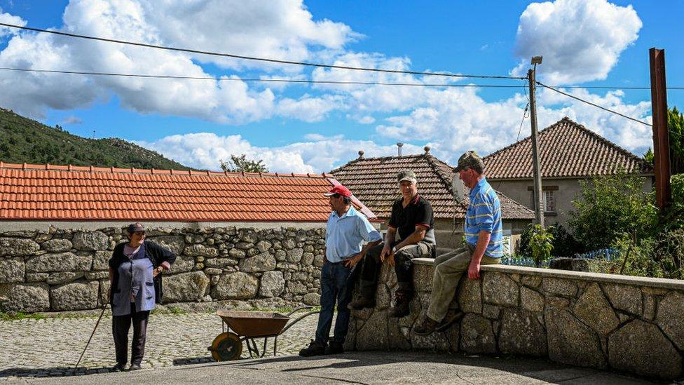 Residents of the village stand in street chatting