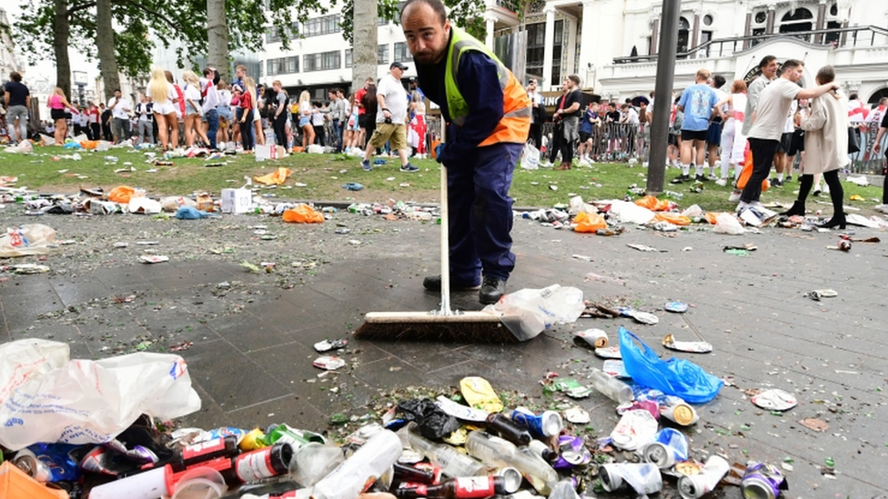 A worker clears rubbish left by fans at Leicester Square