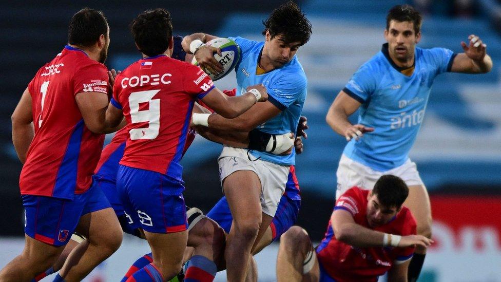 Uruguay's Los Teros Nicolas Freitas (C) runs with the ball as he is tackled by Chile's Los Condores players during a rugby union friendly match between Uruguay and Chile