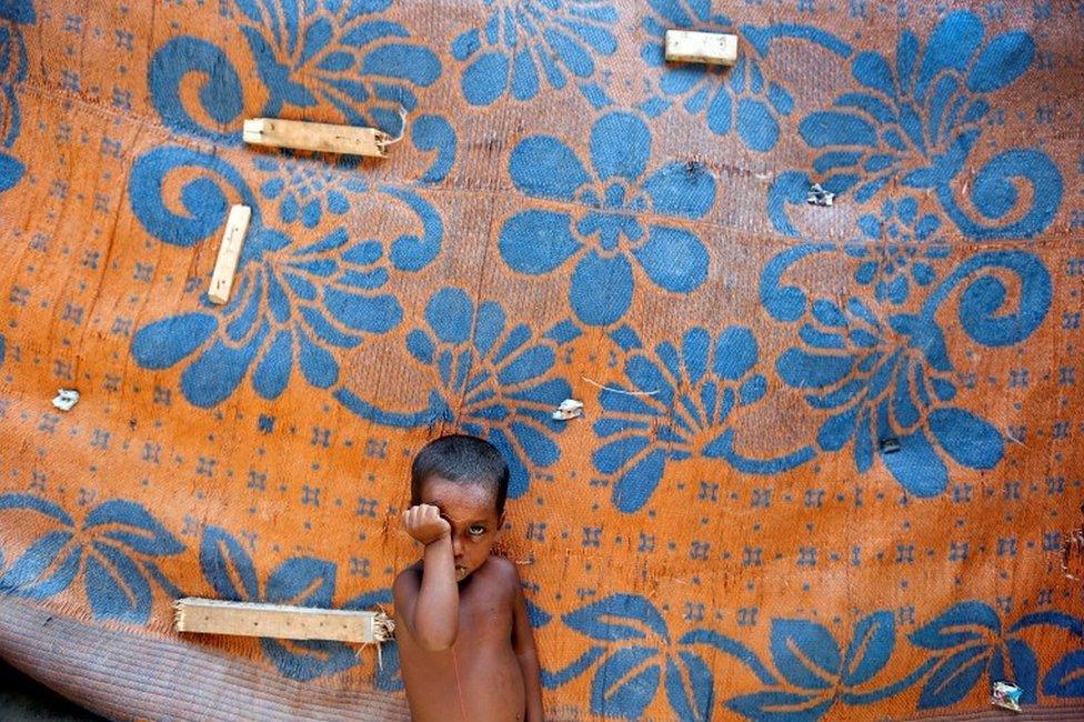 A boy from the Rohingya community stands outside a shack in a camp in Delhi, India August 17, 2017