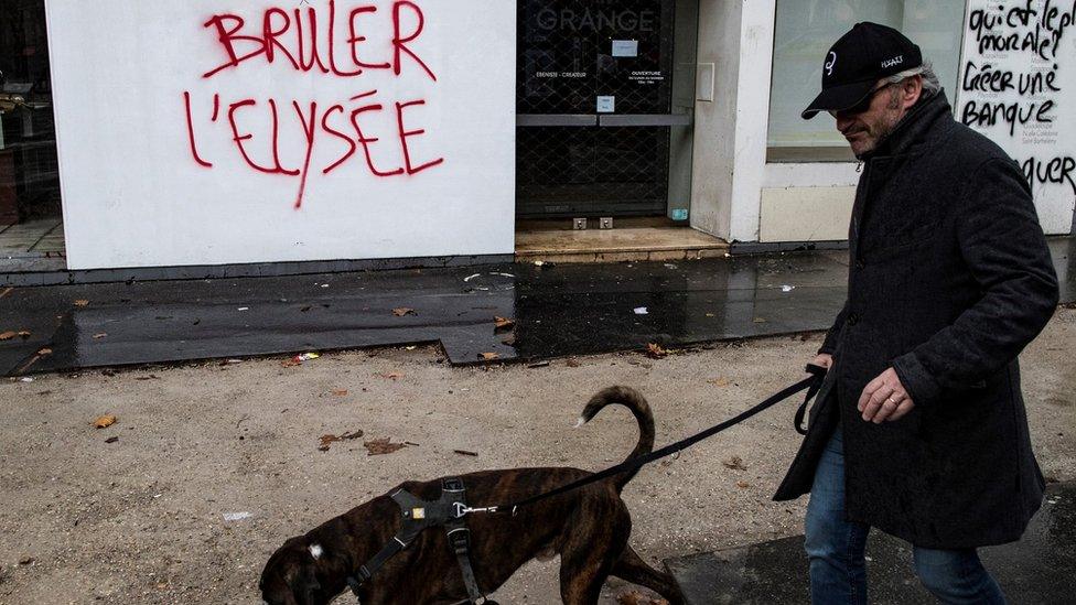 Man walks past graffiti which reads: "Burn the Elysée"