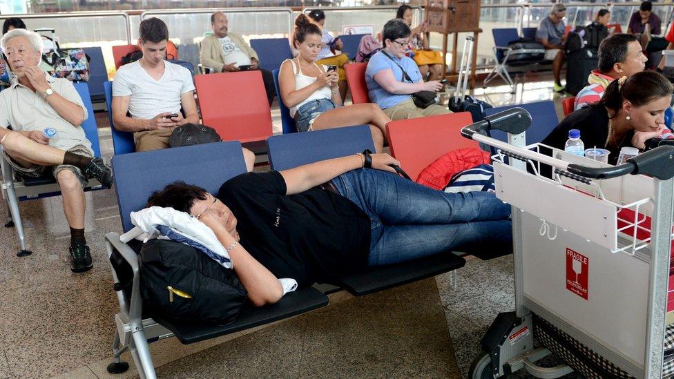 Passengers wait for information on delayed and cancelled flights at the international departure area of Bali's Ngurah Rai Airport in Denpasar on November 4