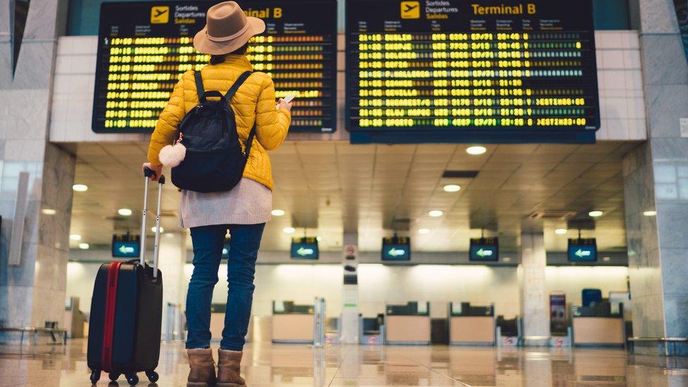 Woman looking at airport departure board