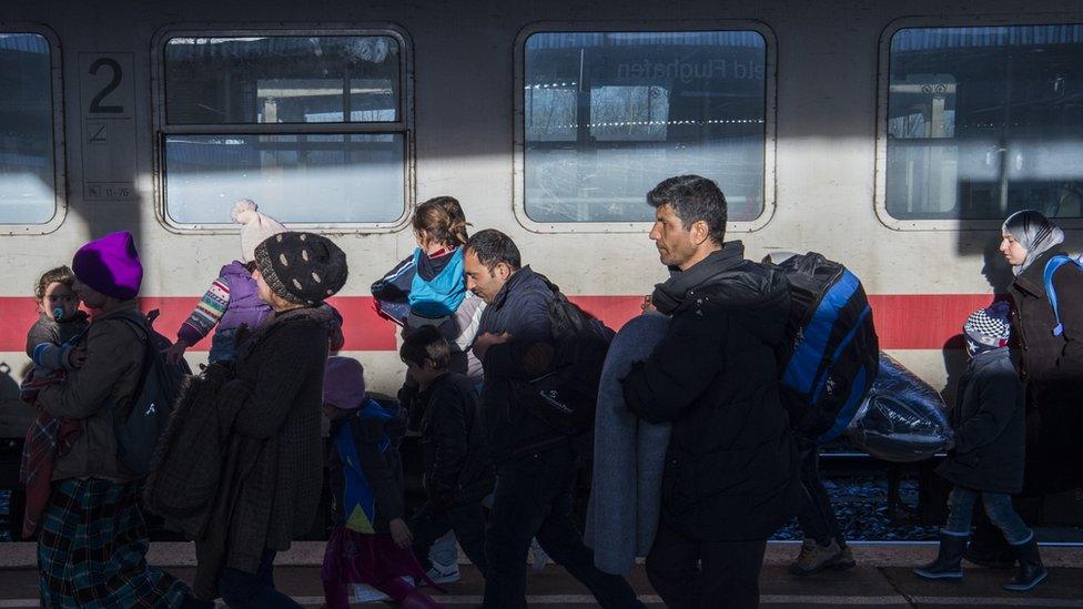 Asylum seekers walk on the platform after getting off a train at the Schoenefeld train station near Berlin on 24 December 2015