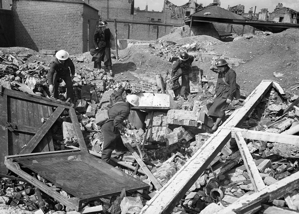 Air Raid Precautions workers - and Rip the dog - search rubble in Poplar, London, 1941