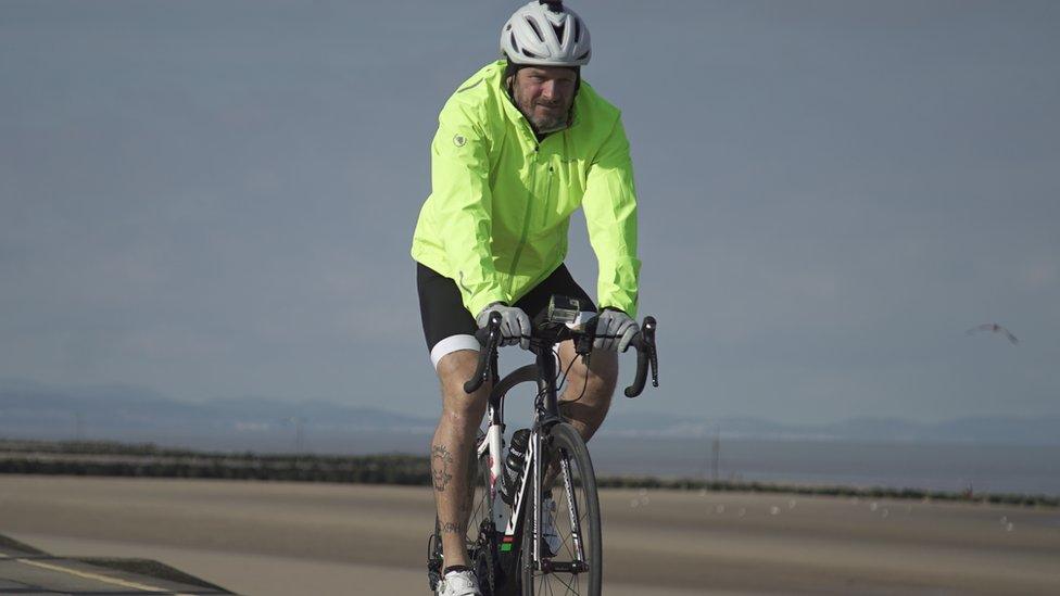 Matt yn seiclo o amgylch Cymru fel rhan o'r ras 'triathlon'