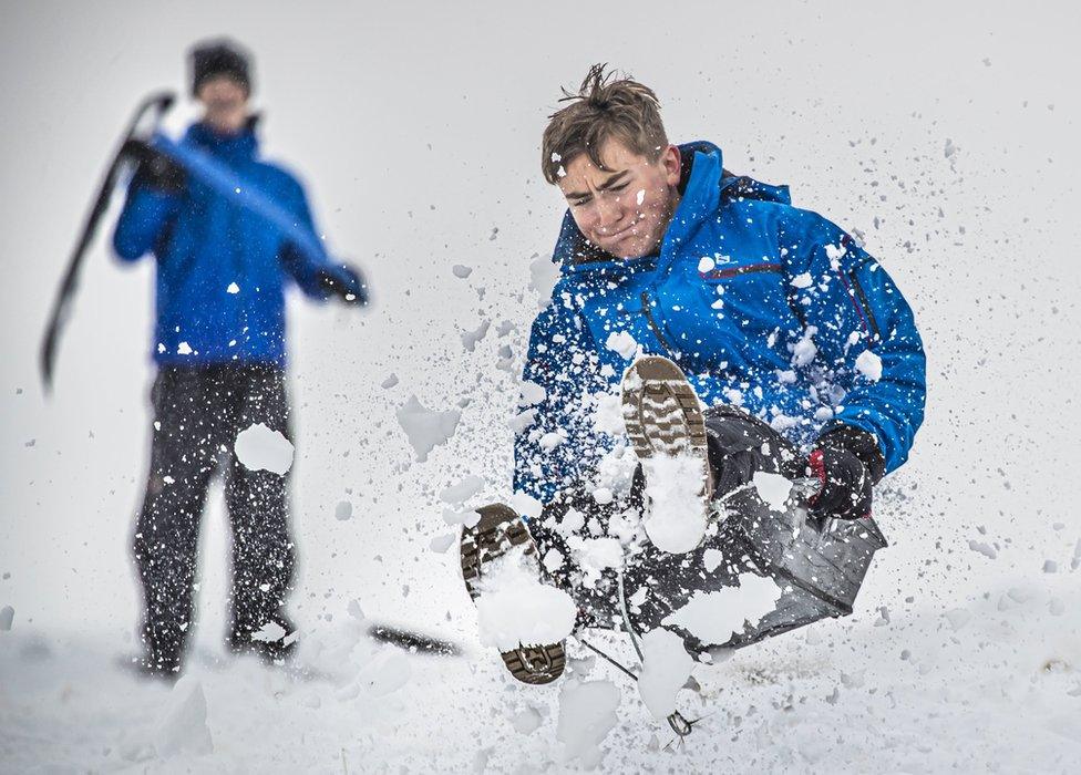 A boy sledges through the snow