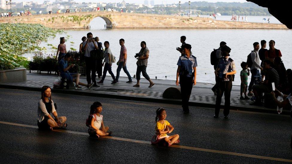 People pose, seated, for photos on an empty road near the West Lake, as police closed off many roads before G20 Summit in Hangzhou, Zhejiang Province, China. 31 August 2016.