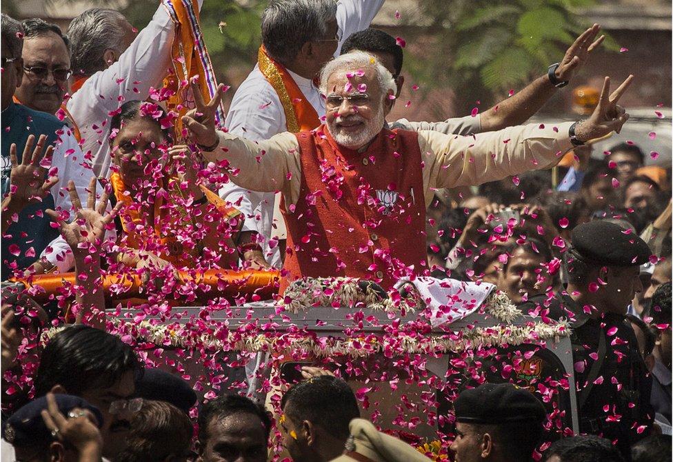 Supporters throw flower petals as Narendra Modi rides in an open jeep in Vadodra