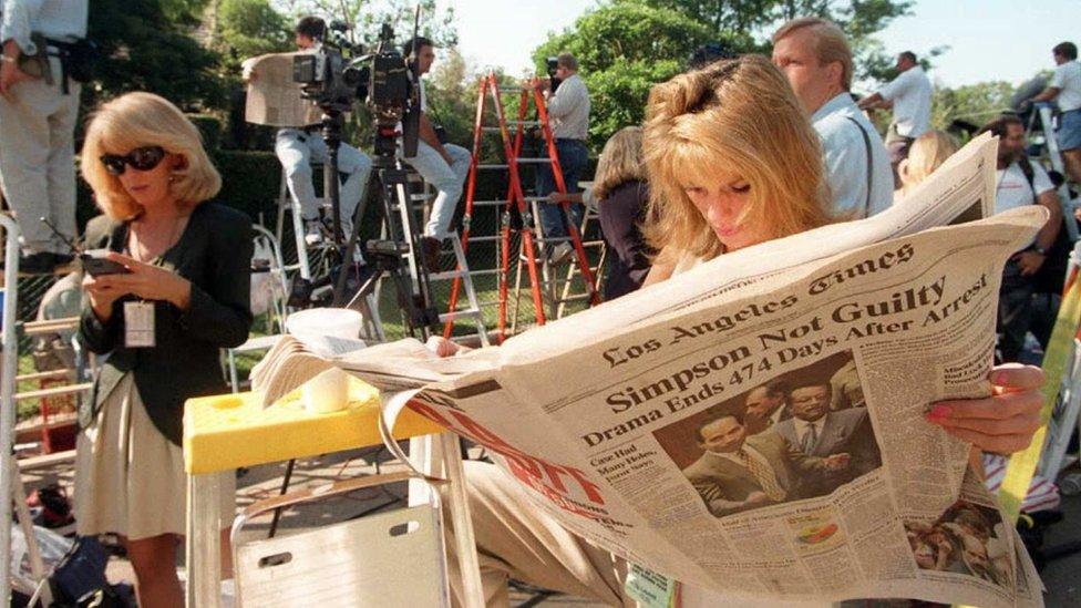 TV reporter Pat Lalama reads a newspaper headlining the not guilty verdicts of O.J. Simpson as she and hundreds of members of the press staked out the Simpson residence in Brentwood, CA.