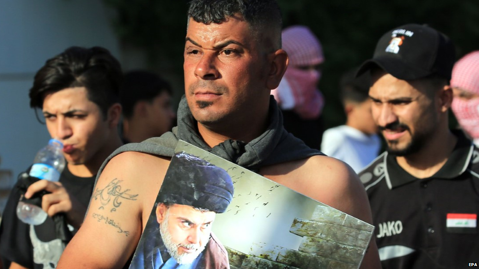 An Iraqi protester carries a poster of Shia leader Moqtadr al-Sadr