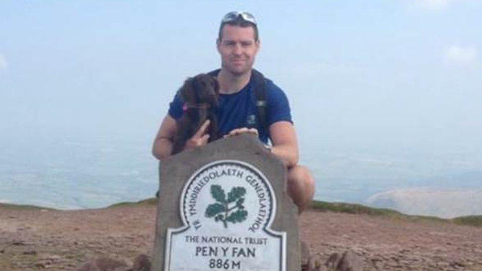 Detective Inspector Terry Hopkins on top of Pen Y Fan holding a small dog