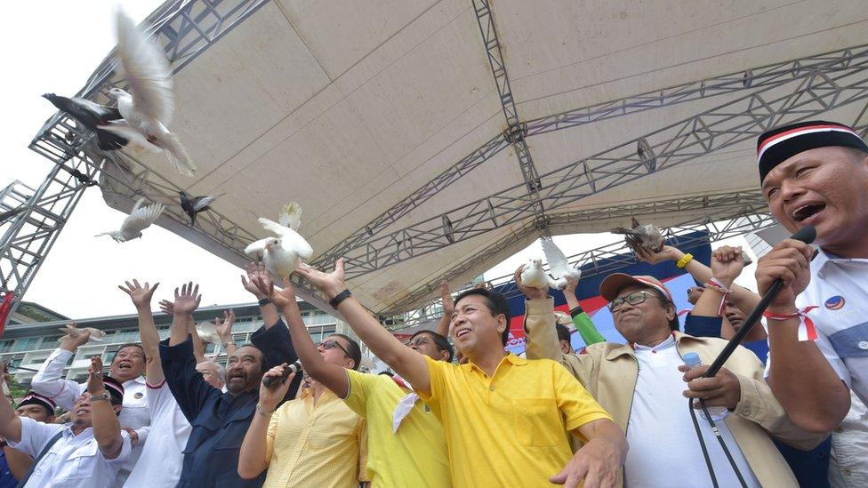 Indonesian parliament speaker Setya Novanto (3 R in yellow) and head of Nasional Demokrat Party Surya Paloh (3 rd L in dark blue) release pigeons as Indonesian people hold a pro-government rally