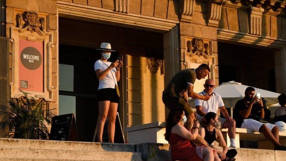 People sit on the stairs of the National Art Museum of Barcelona