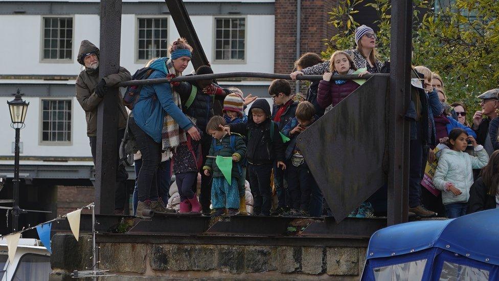 People stand to see Little Amal