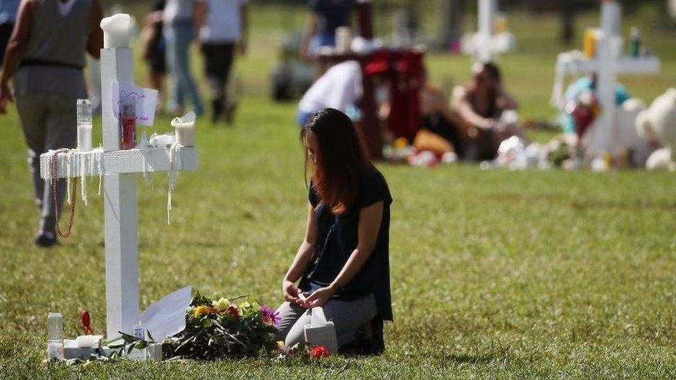 A young girl sits at a temporary memorial in Parkland, Florida. Photo: 17 February 2018