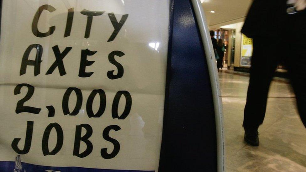 A city worker walks past an Evening Standard newspaper stand in Canary Wharf, London in 2008