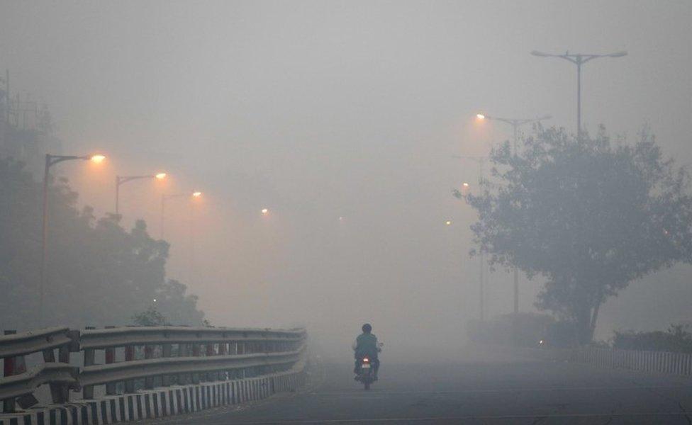 A man rides a scooter on a road enveloped by smoke and smog, on the morning following Diwali festival in New Delhi, India, Monday, Oct. 31, 2016.