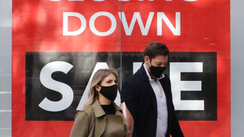 Couple walk past closing down sale sign