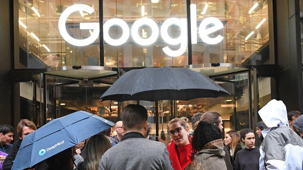 People standing with umbrellas outside Google office