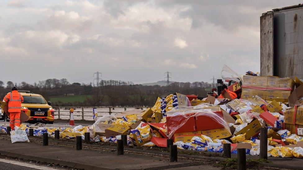 Workers clear up Wotsits and Quavers crisps from the M6 motorway northbound after the wind overturned lorries on the carriageway