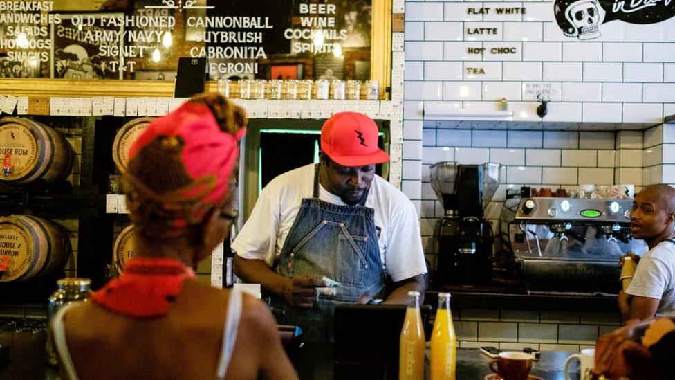 A woman buys a drink from the hipster coffee store 'House of Machines' on March 31, 2017 in Cape Town, South Africa.