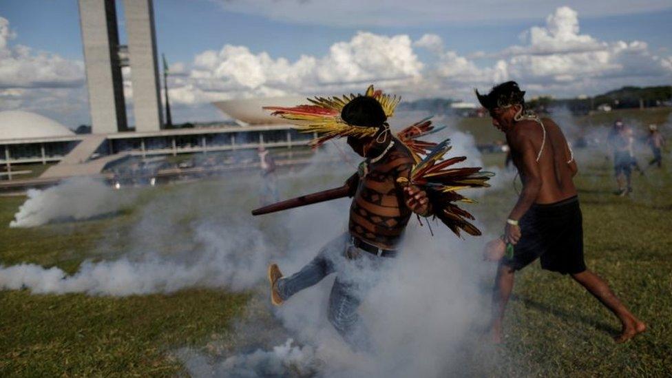 Indigenous protesters kick at canisters of tear gas at a demonstration in Brasilia on 25 April 2017