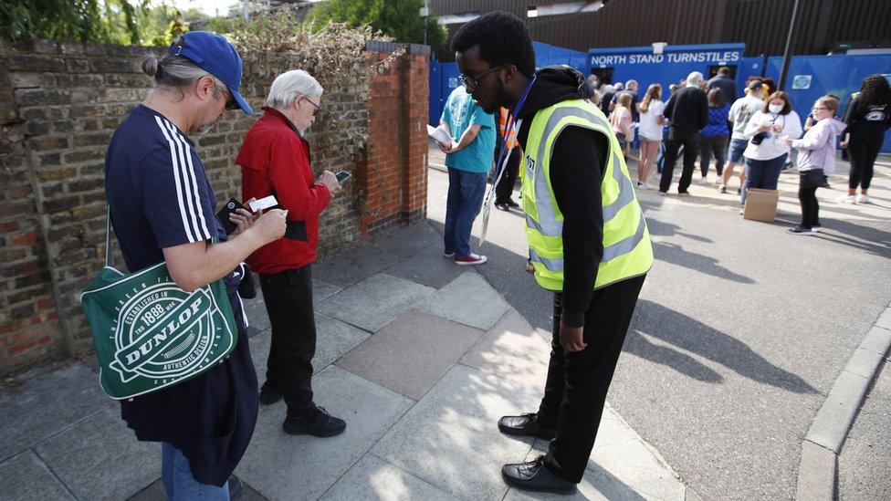 Fans show their Covid status to stewards outside the Women's Super League game between Chelsea and Everton on Sunday