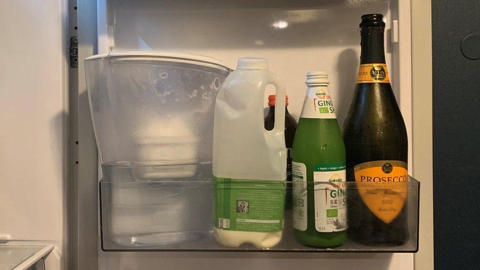 A fridge door with an open bottle of prosecco