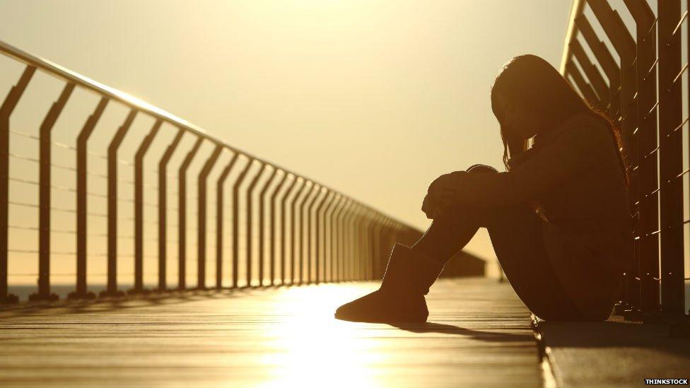 A girl sitting alone on a bridge