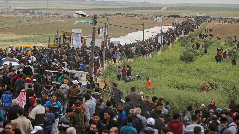 Palestinians march past a tent city erected along the border with Israel east of Gaza City. 30 March 2018