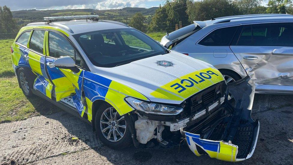 Police cars showing damage after being rammed by tractor