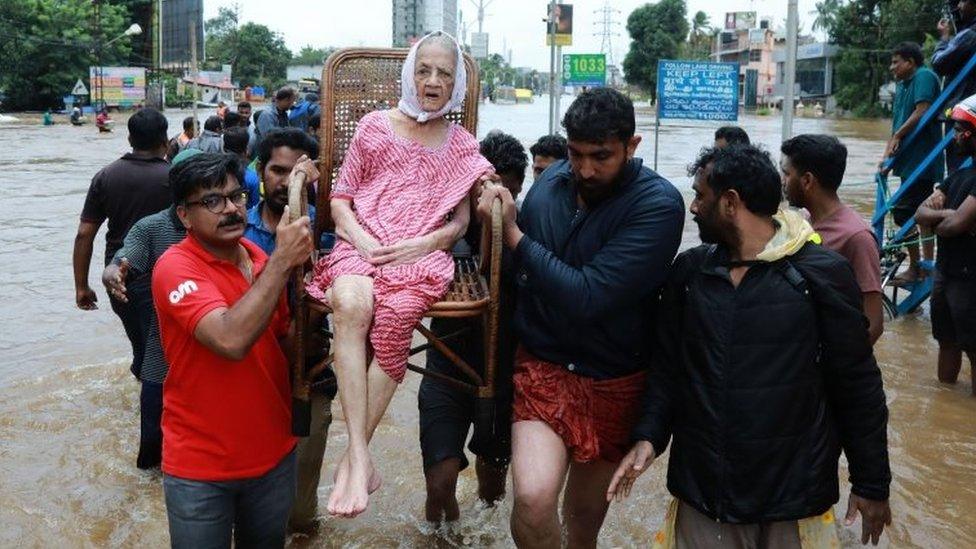 Indian volunteers and rescue personal evacuate local residents in a residential area in Ernakulam district, in the Indian state of Kerala, on 17 August 2018