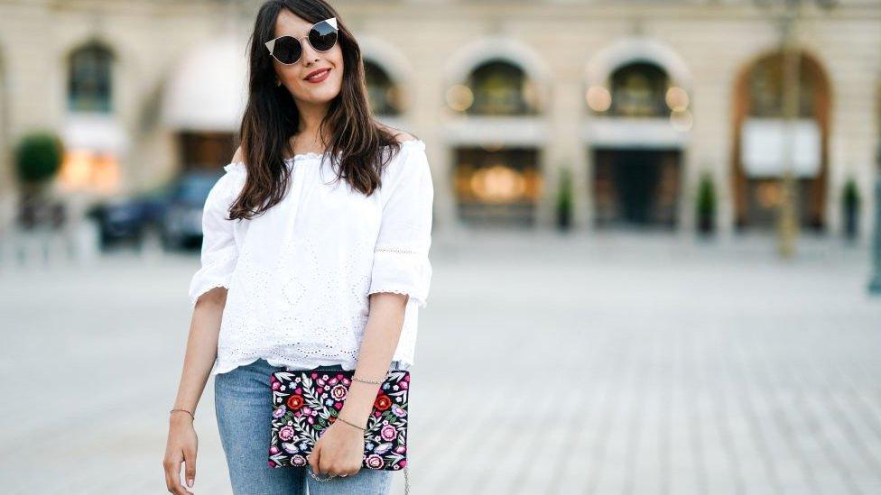 Fashion blogger Sarah Benziane wears a New Look white lace off-shoulder top and New Look jeans in Paris