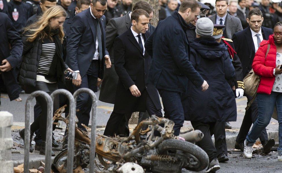 French President Emmanuel Macron (centre) assesses damage following the "Yellow Vests" protest a day earlier, next to the Champs Elysee in Paris, France, 2 December 2018