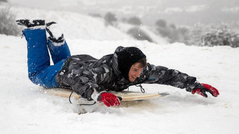 James Ring uses a surf board to sledge down a snow covered hill in Wye National Nature Reserve near Ashford in Kent