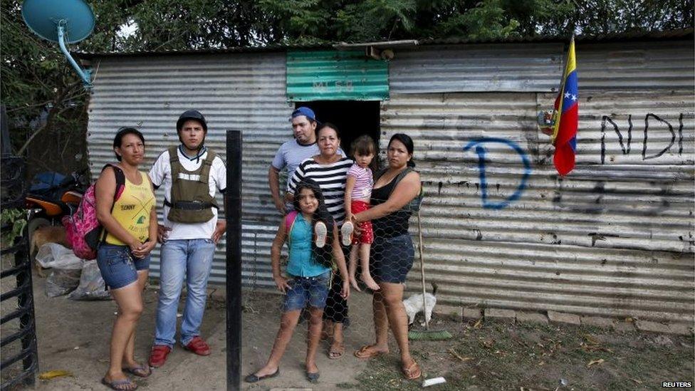 A family poses for a picture at the door of their house, which was marked for demolition with the letter D, during a special deployment at San Antonio in Tachira state, Venezuela, on 25 August, 2015.