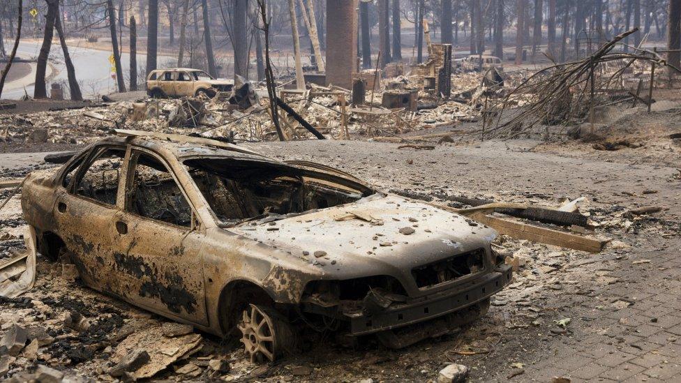 A burned out vehicle sits in the driveway of a Paradise home in Butte County, California, 11 November 2018