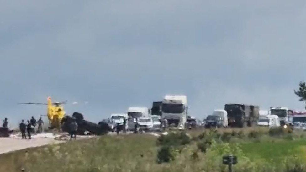 Scene of crash on A11 near Mildenhall showing air ambulance on carriageway and car on its roof