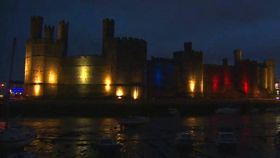 Caernarfon Castle lit up with French tricolour