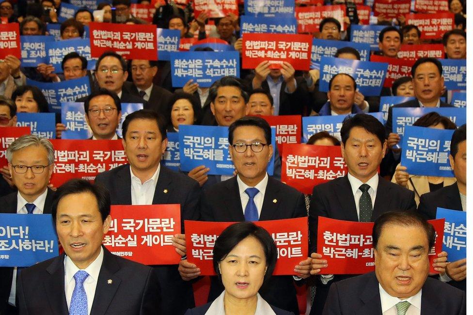 Dozens of politicians from the main opposition Democratic Party, including its chief Choo Mi-ae (centre, front row), hold up signs protesting against the president on 1 November 2016.