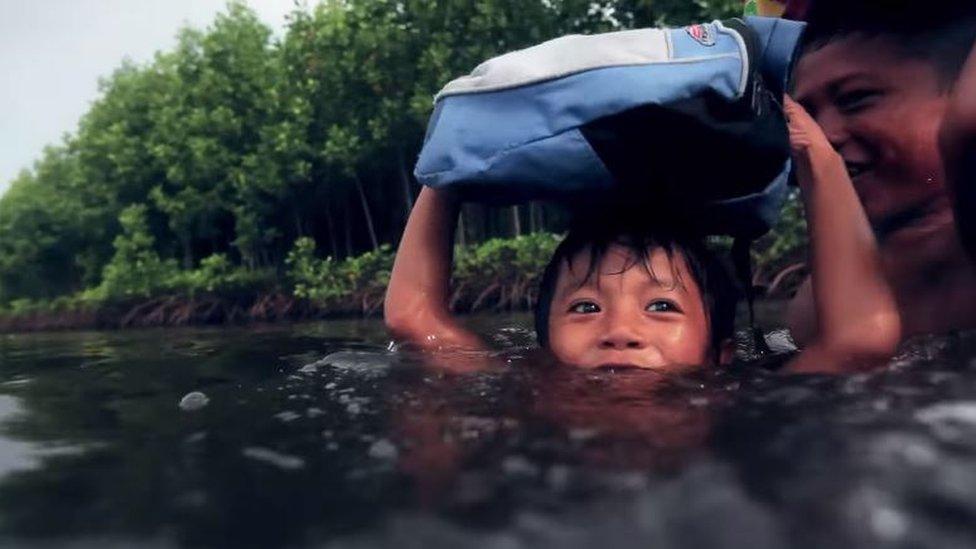 Young boy wading to school