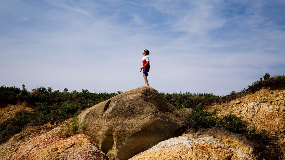 A boy looks at the partial eclipse of the sun from a beach in Chilmark, Massachusetts, USA, 21 August 2017