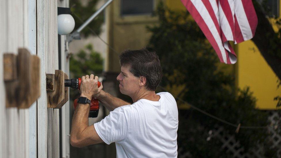 A man helps board up a building in North Carolina