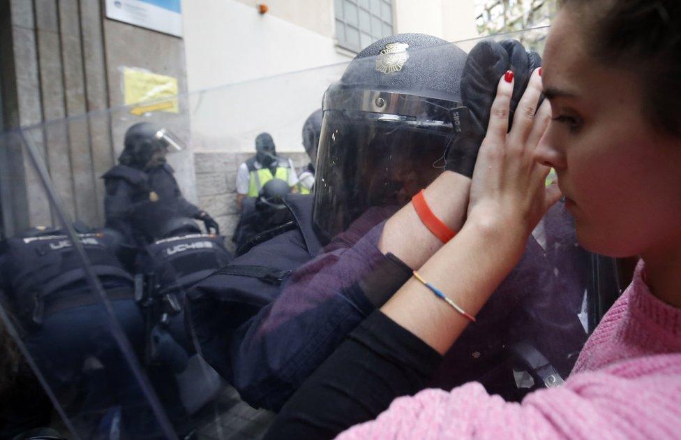 Spanish police push a girl with a shield outside a polling station in Barcelona, on October 1, 2017