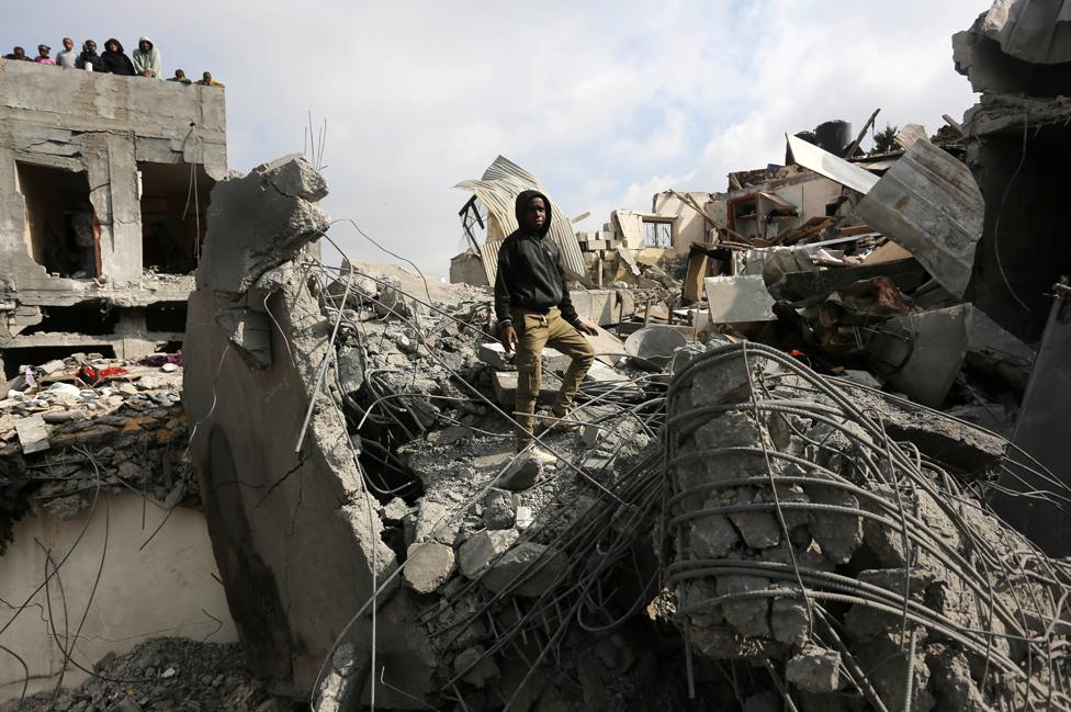 A man walks among ruined buildings